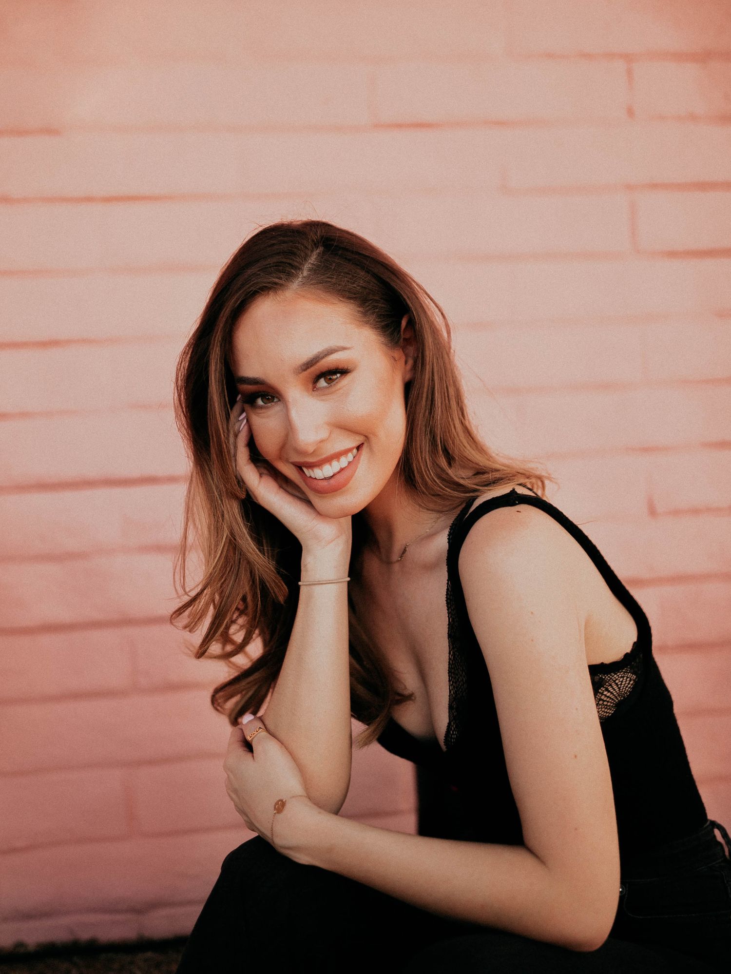 Portrait against pink brick wall showcasing natural lighting and casual pose.