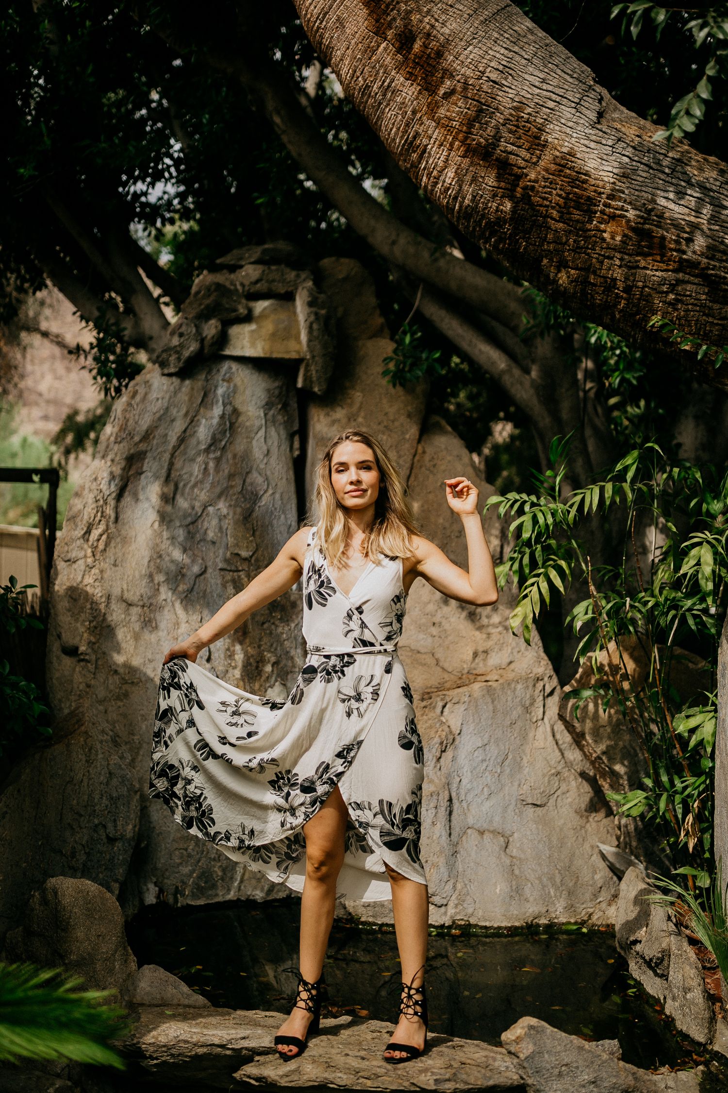 Fashion photo of floral dress against stone wall and tropical garden backdrop.