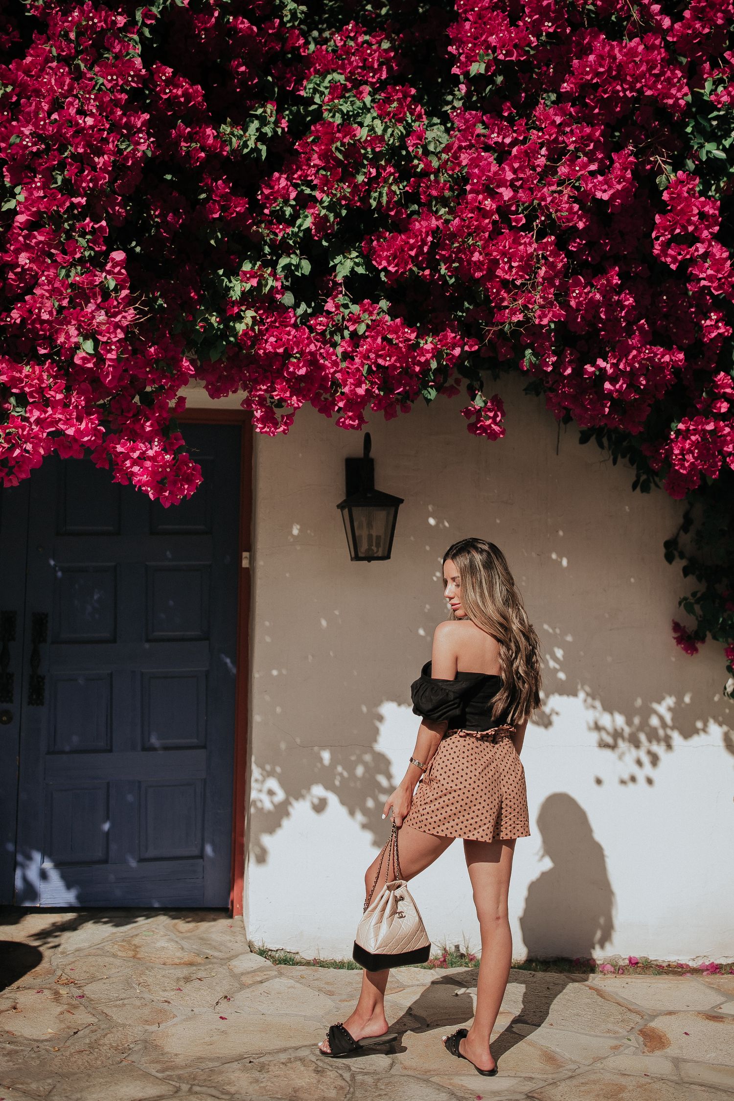 Fashion photo with bright pink bougainvillea flowers against beige stucco wall.