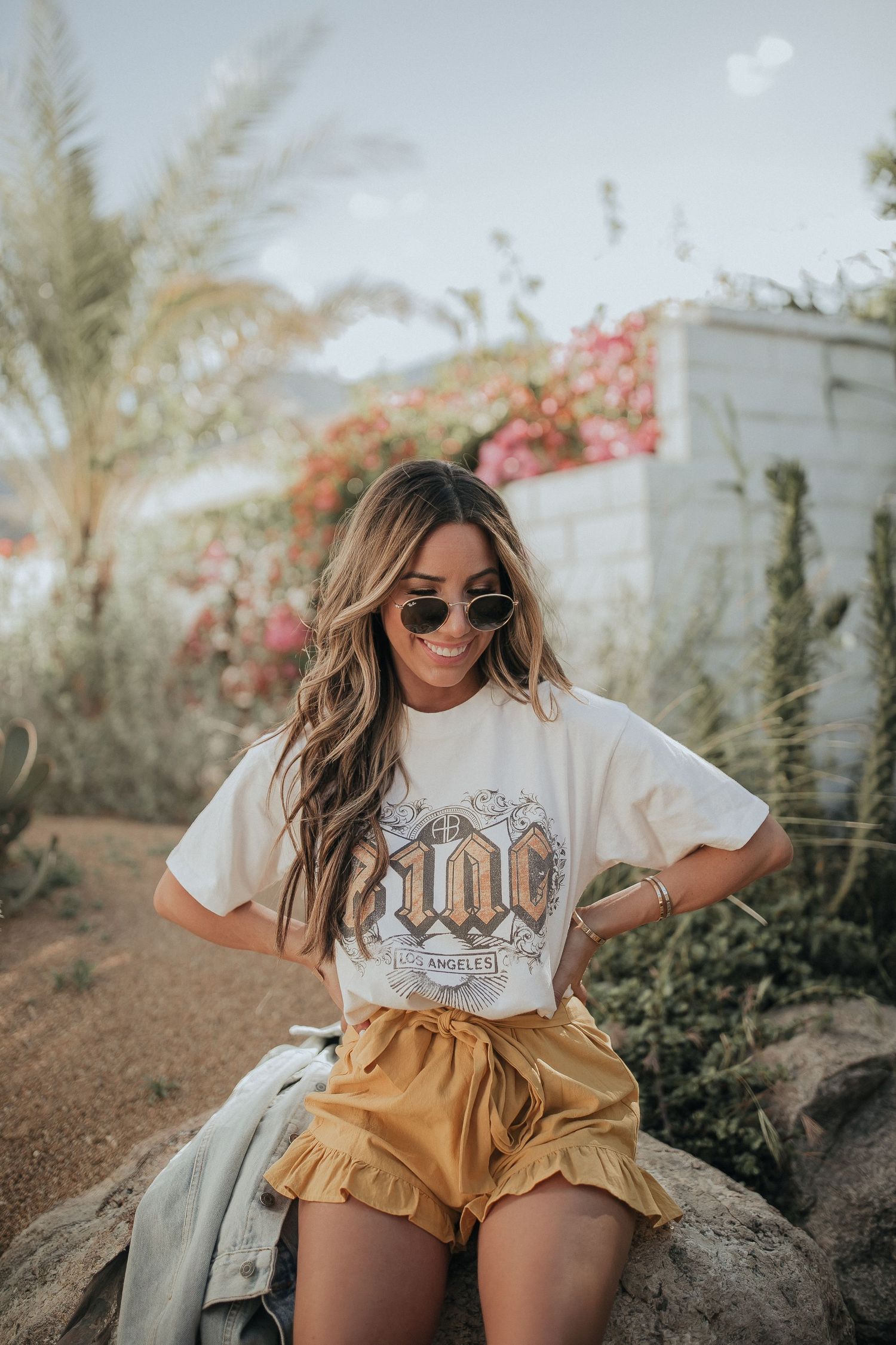 Casual desert fashion shoot featuring mustard shorts and graphic tee against desert landscape.