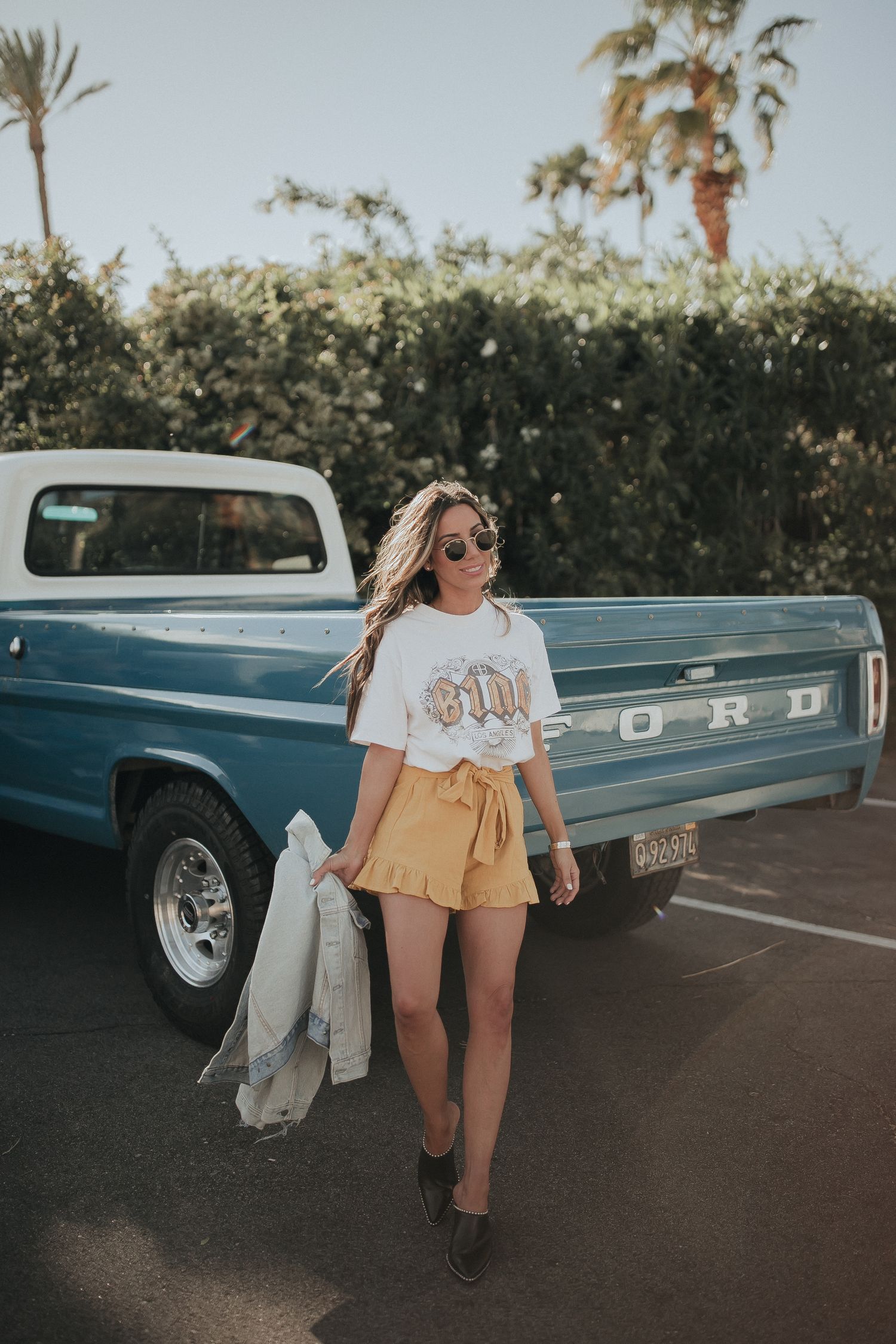 Classic vintage Ford pickup truck parked in palm tree lined desert setting.