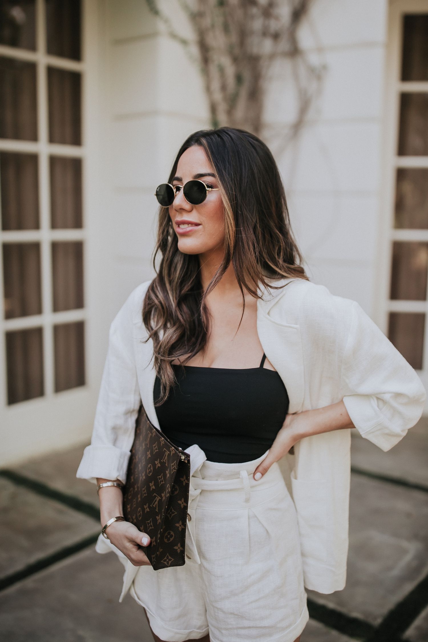 Stylish monochrome outfit against white architectural backdrop with sunlit windows.