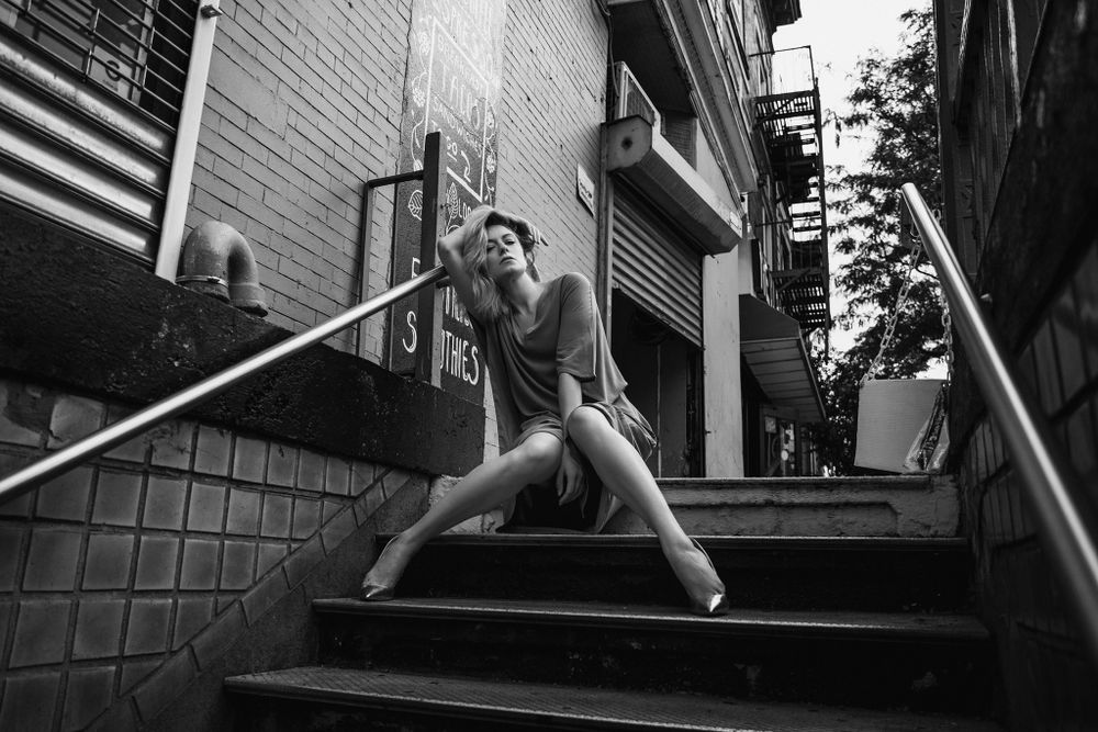 Athletic figure in dramatic pose on urban stairwell in black and white.