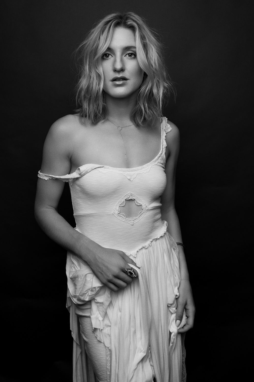 Artistic black and white portrait featuring a distressed white dress against a dark background.