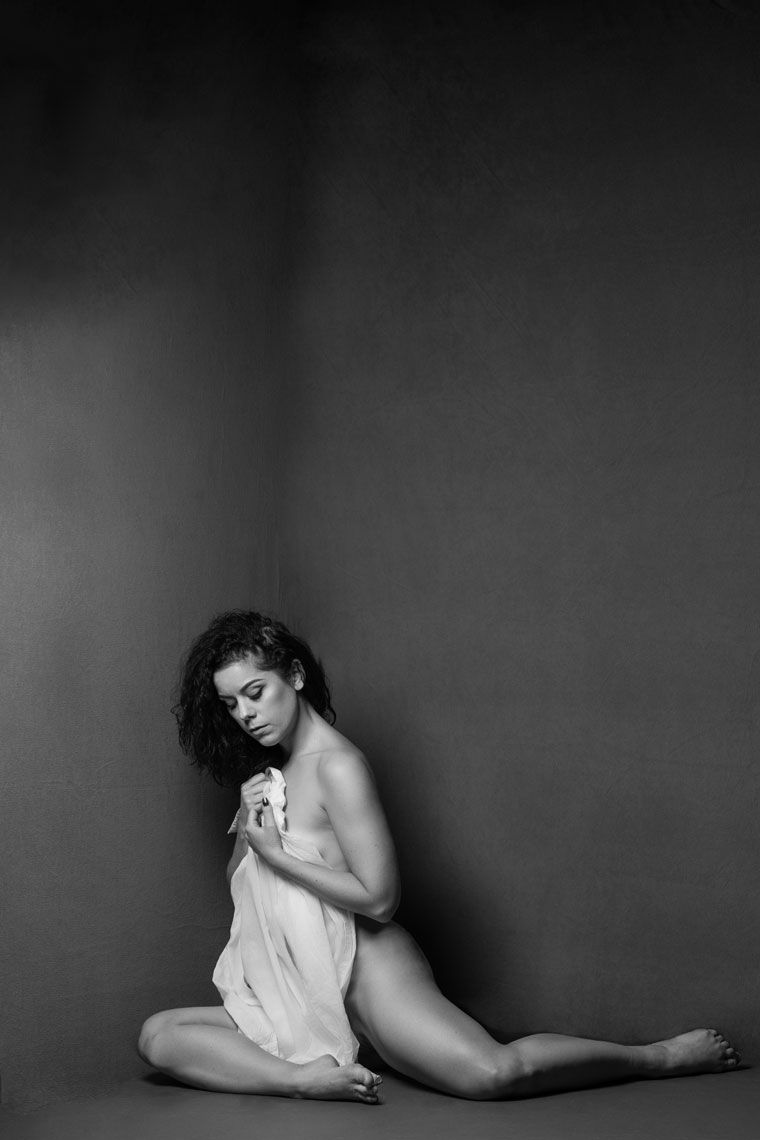 Graceful figure study in monochrome featuring draped fabric and contemplative pose.