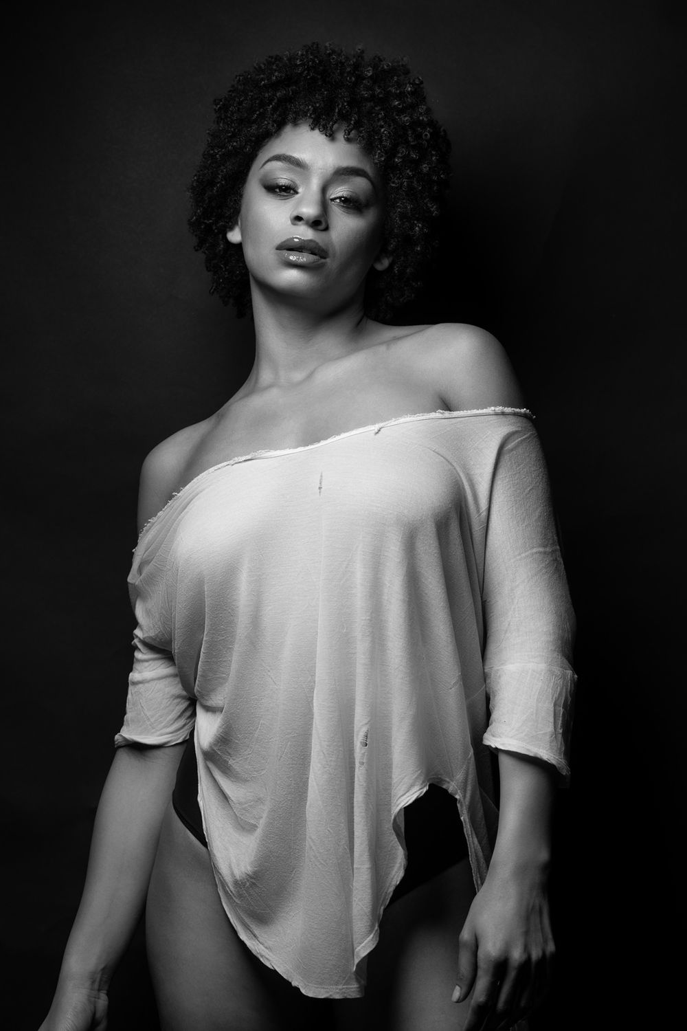 Fashion portrait in monochrome featuring off-shoulder top and natural hair texture.