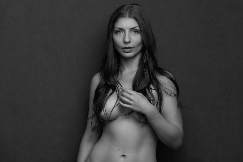 Artistic black and white nude portrait with subject covering chest.