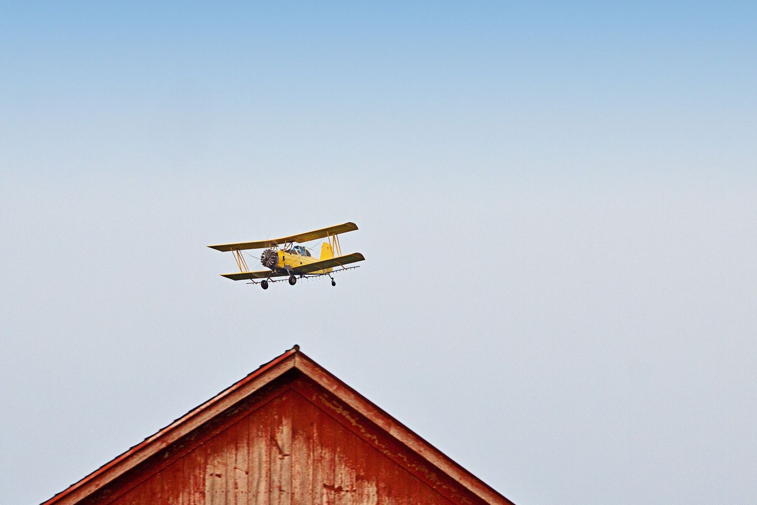 Crop duster airplane over barn