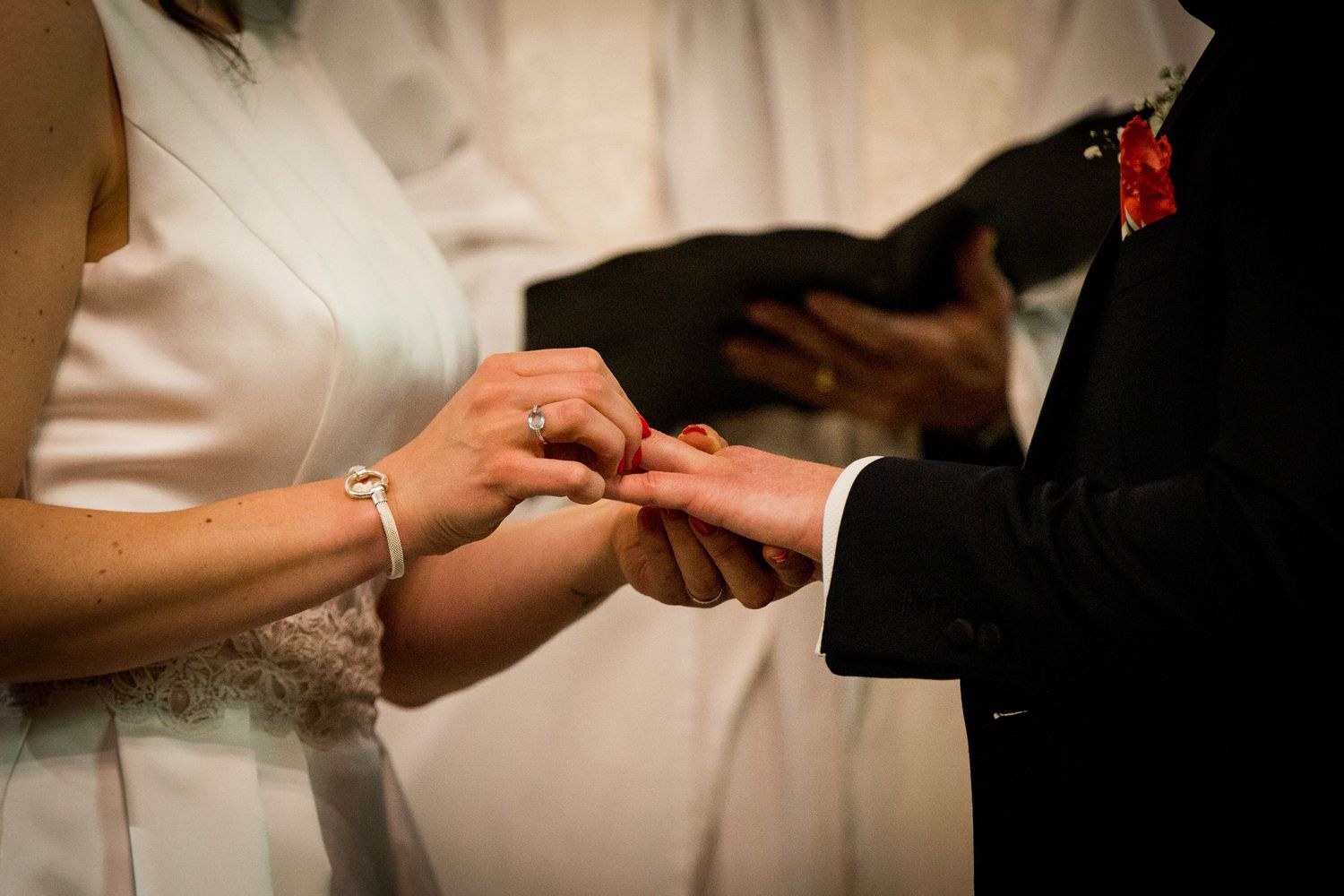 Close-up of hands exchanging rings during wedding ceremony.