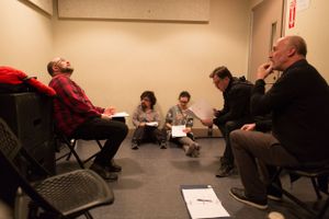 People seated in a meeting room during what appears to be a script reading session.