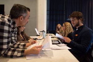 Group of people seated at tables reviewing documents during a workshop or meeting.