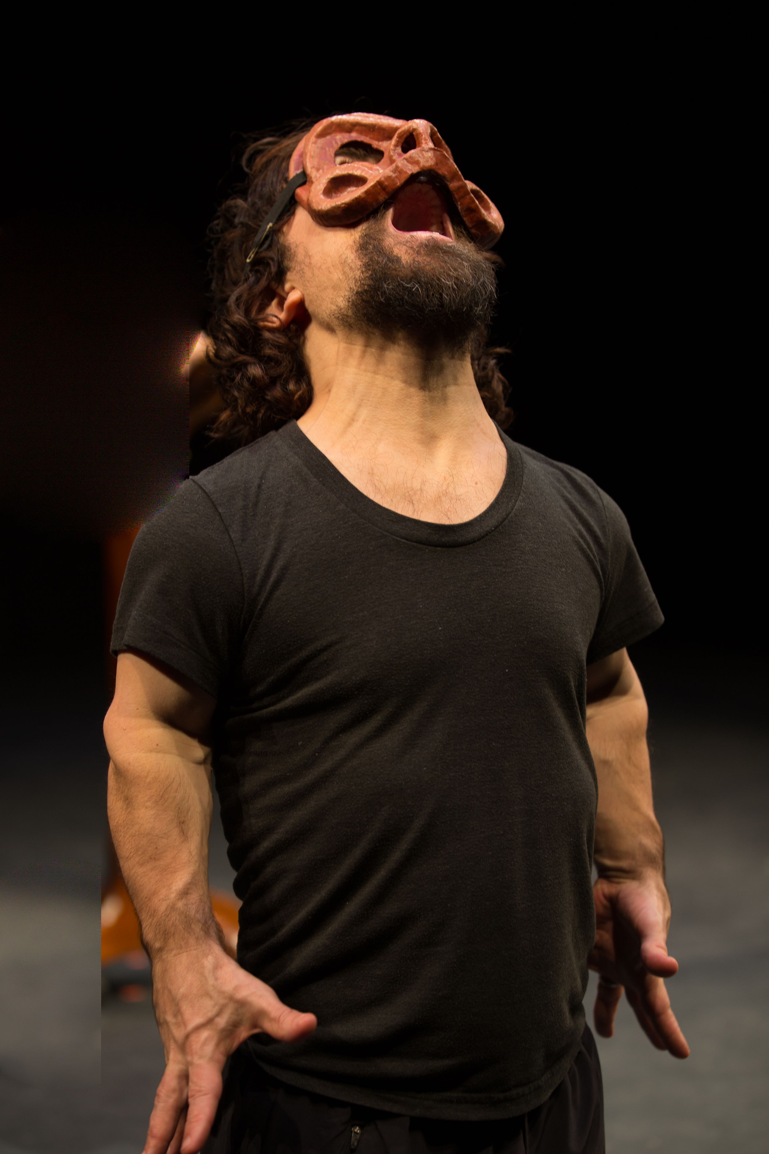 A performer in a black shirt expressing intense emotion during a theatrical performance.