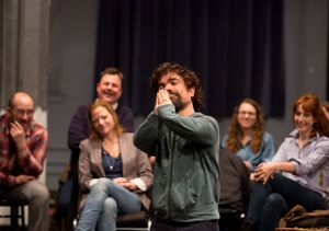 Audience members watching and reacting during what appears to be a theatrical performance.