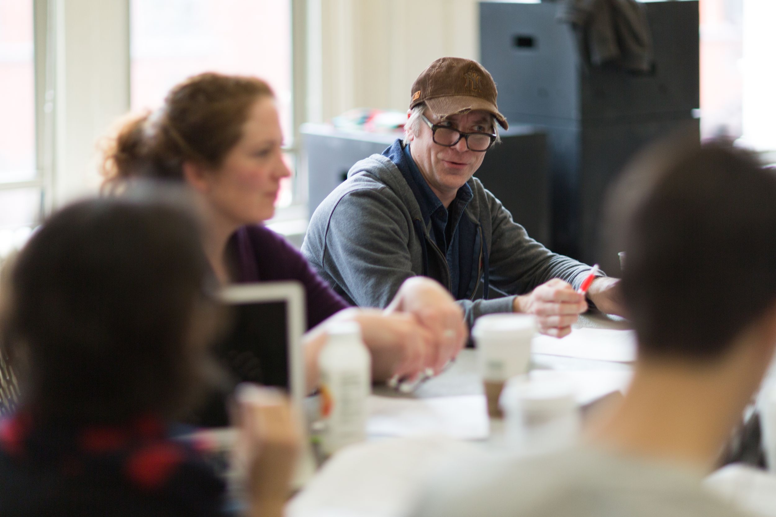 People gather around a table during what appears to be a meeting or discussion.
