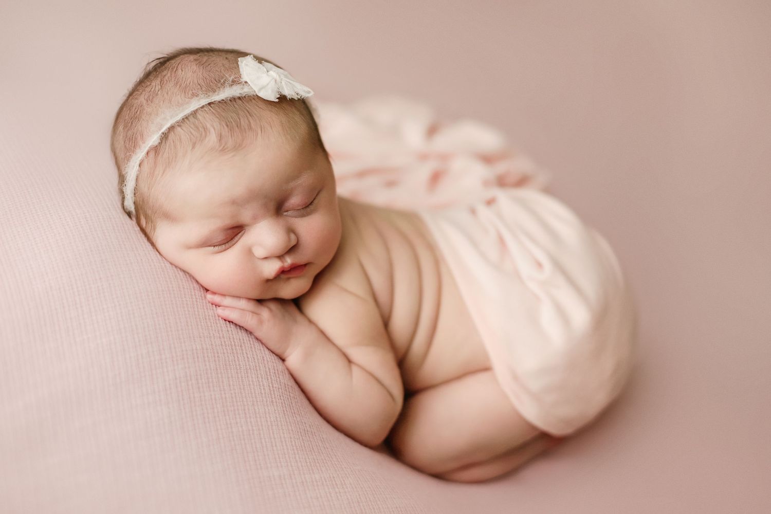 fine art newborn studio portrait of baby girl in pink with headband