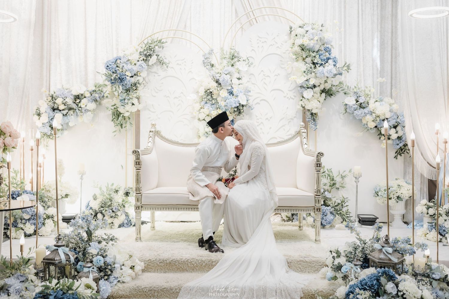 Elegant white wedding venue decorated with blue floral arrangements and crystal chandeliers.
