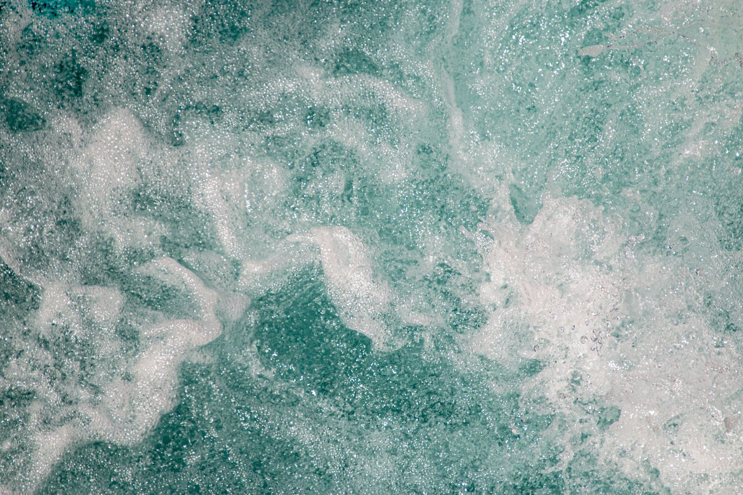 White water churns in vibrant turquoise, capturing the raw energy of a rushing stream.