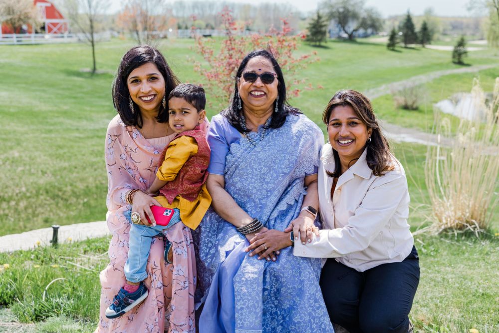 A family group poses together on grassy hill with pond in background.