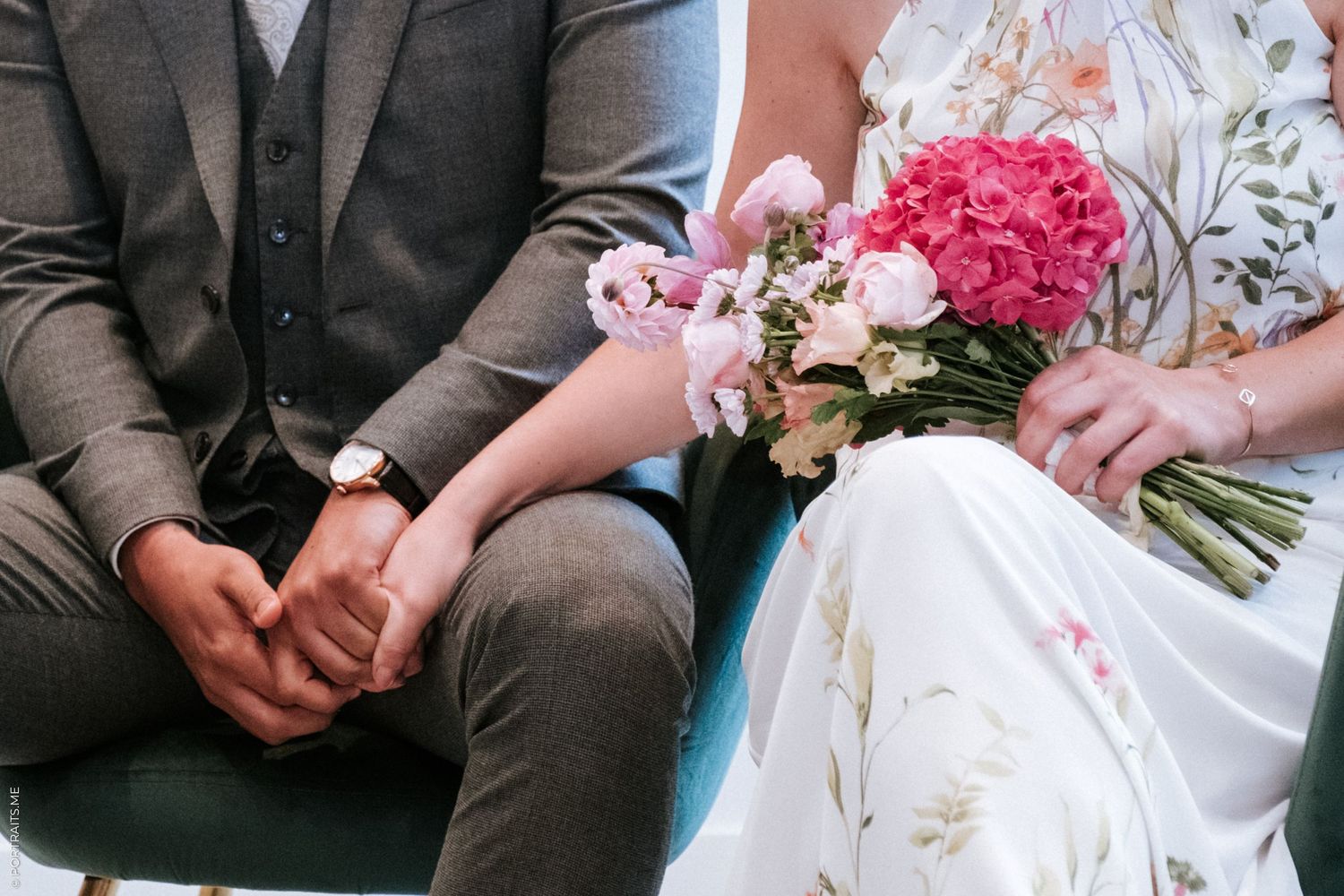 Close up of hands and a pink bouquet during an intimate wedding ceremony.