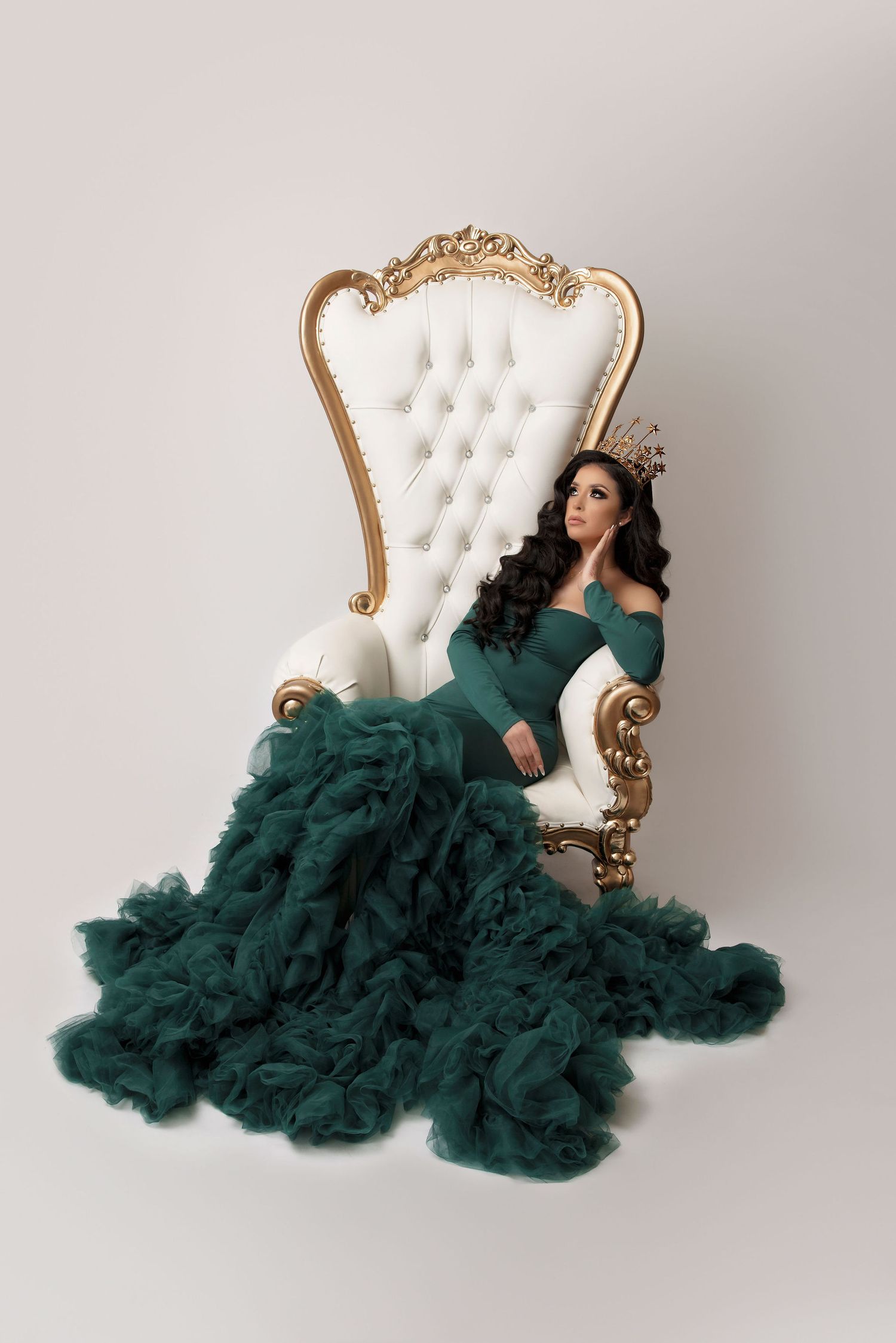Dramatic fashion photo in emerald green tulle gown on white baroque throne chair.