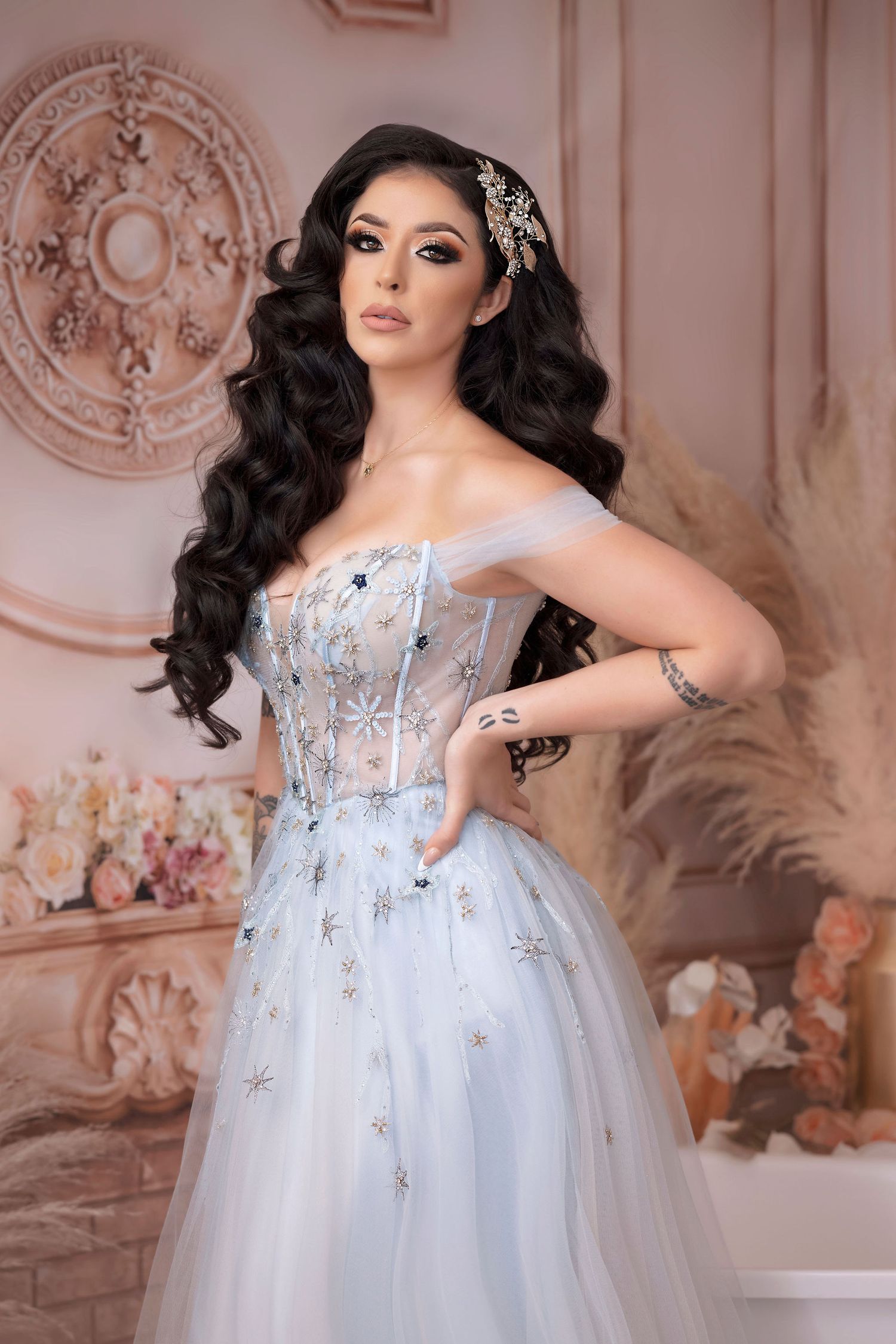 Close-up fashion portrait in crystal-embellished blue corset gown with wavy dark hair.
