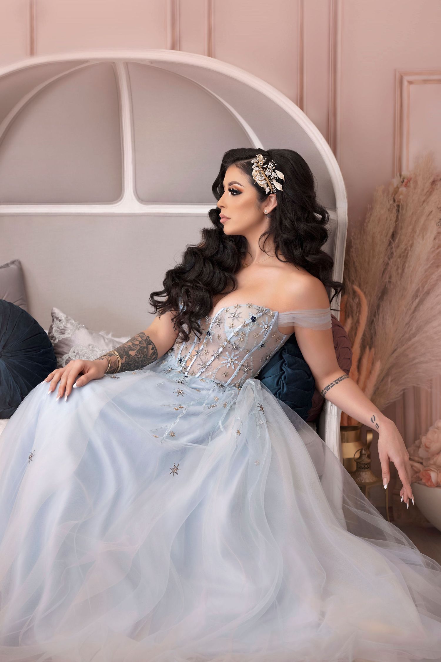Side profile portrait in blue princess gown against architectural pink backdrop.