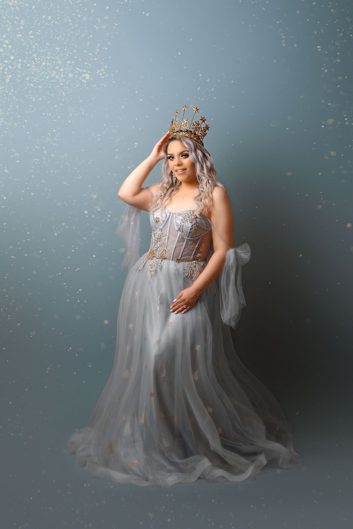 Dreamy silver princess gown with sparkling crown against moody gray background.