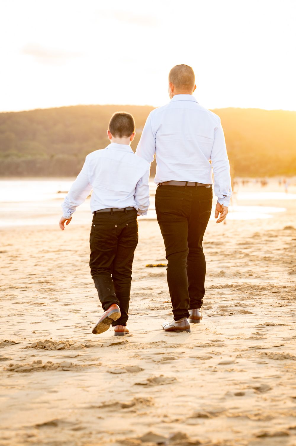 Son and Dad walking away on the sand during sunset