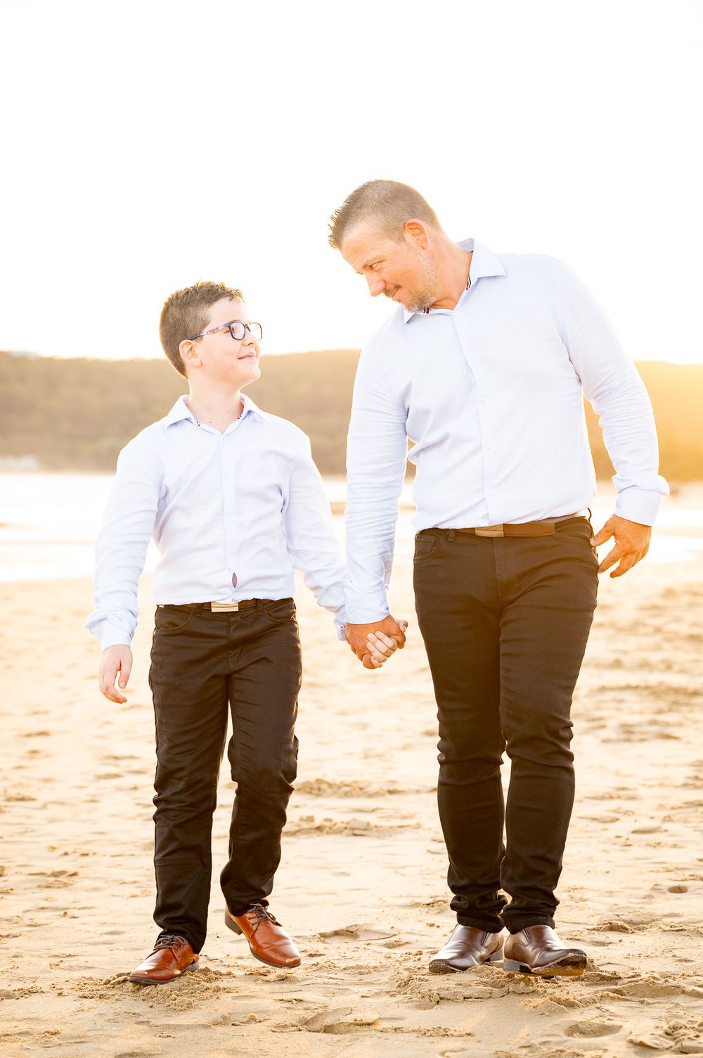 Dad and son walking together at sunset looking at each other