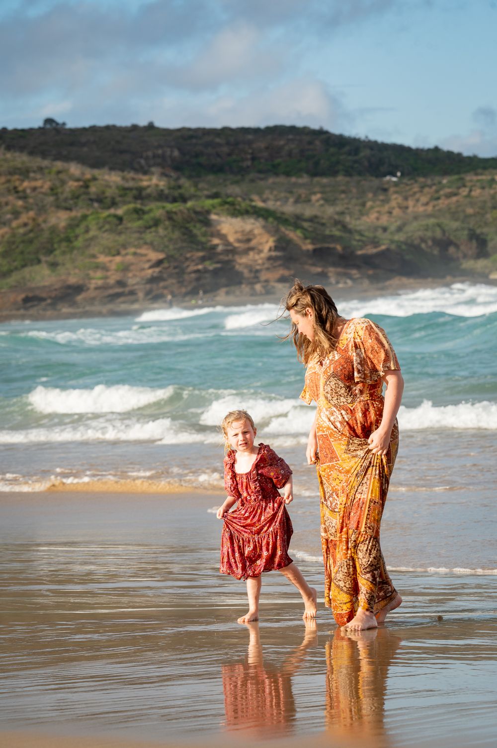 Mum and daughter running by the oceans edge during a photoshoot