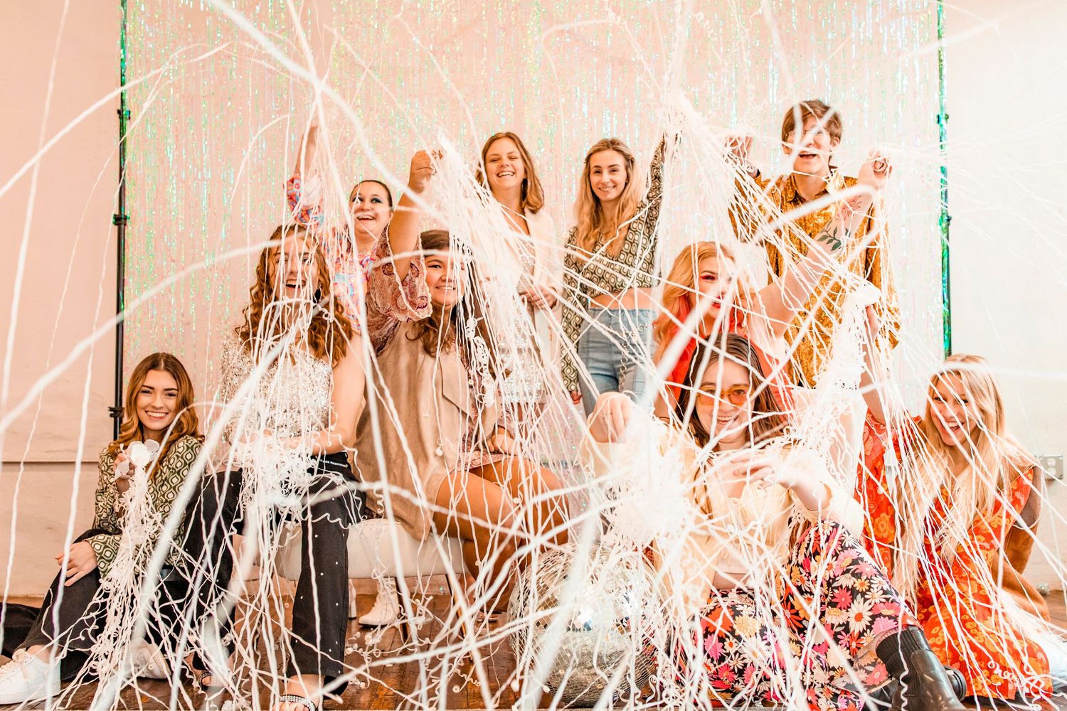 Excited group of women celebrate with white streamers and confetti at a fun indoor event.
