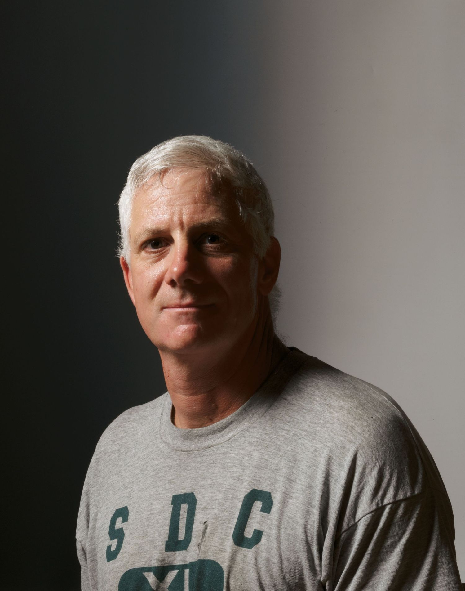Portrait of person wearing grey t-shirt against gradient background.