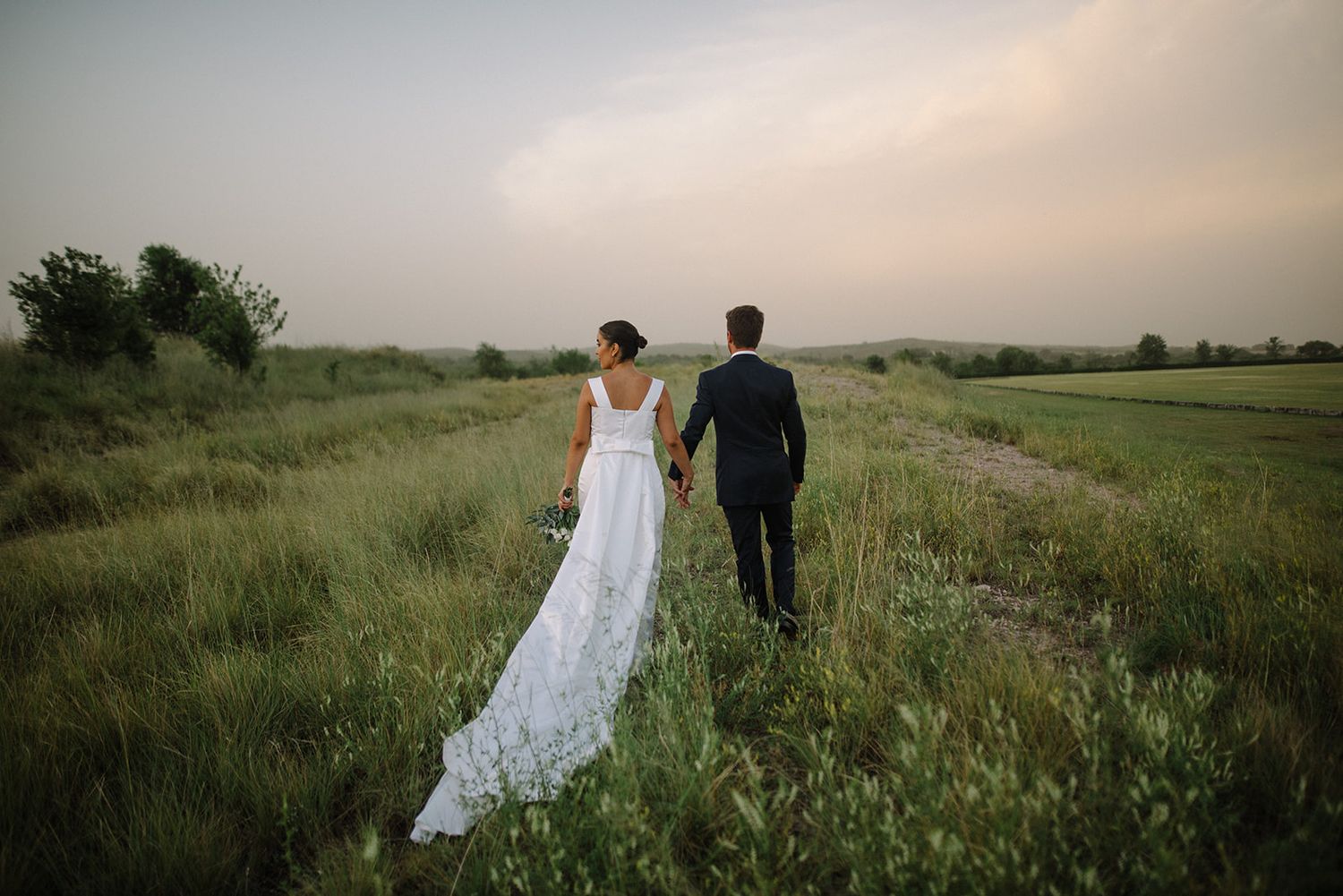 A couple on their wedding day walking on the fields of Tuscany in Italy