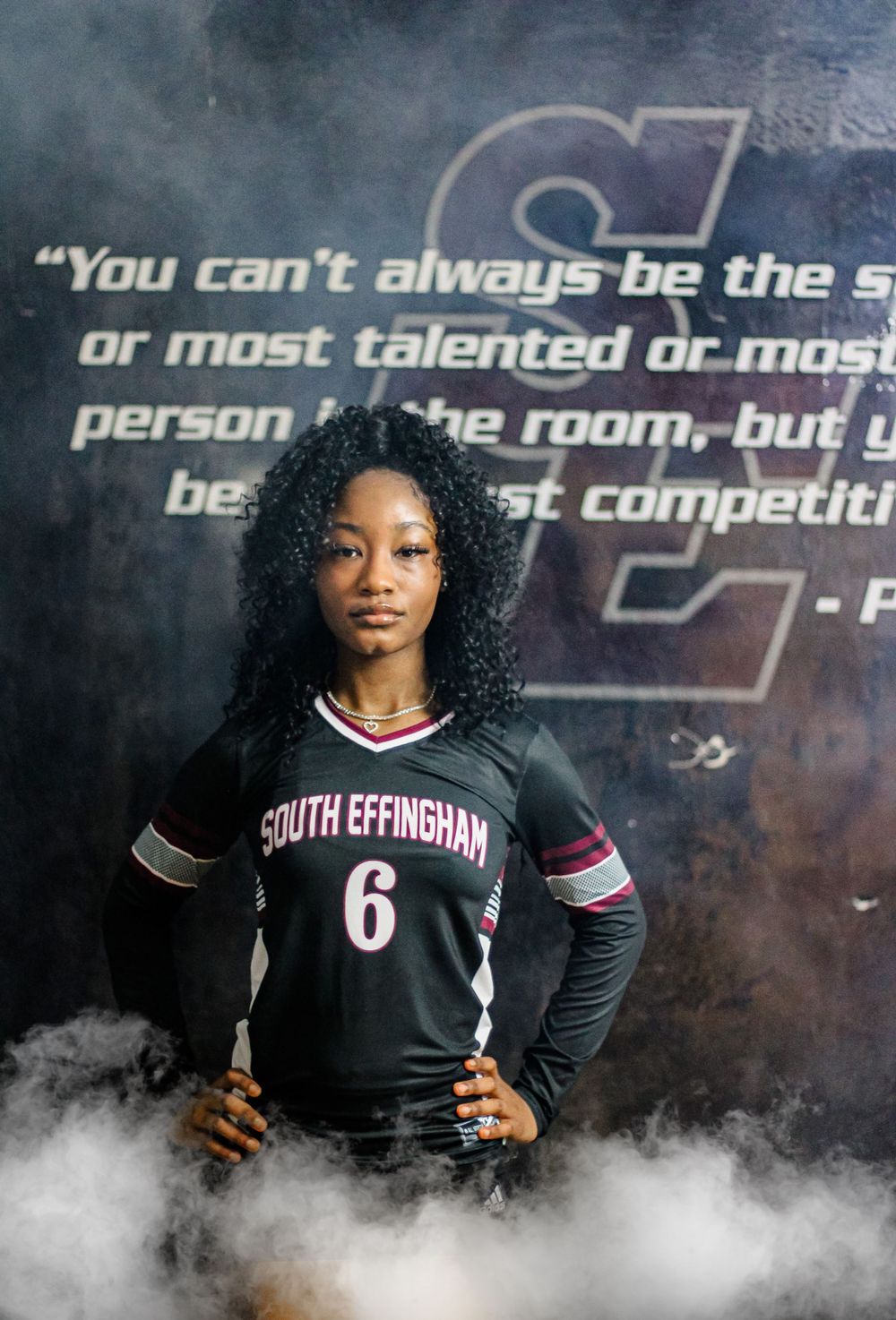 Volleyball player in jersey number 6 poses with motivational quote and dramatic smoke effects.