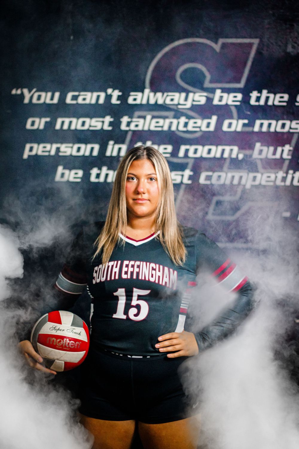 A volleyball player in a South Effingham uniform poses with a ball against a motivational quote backdrop.