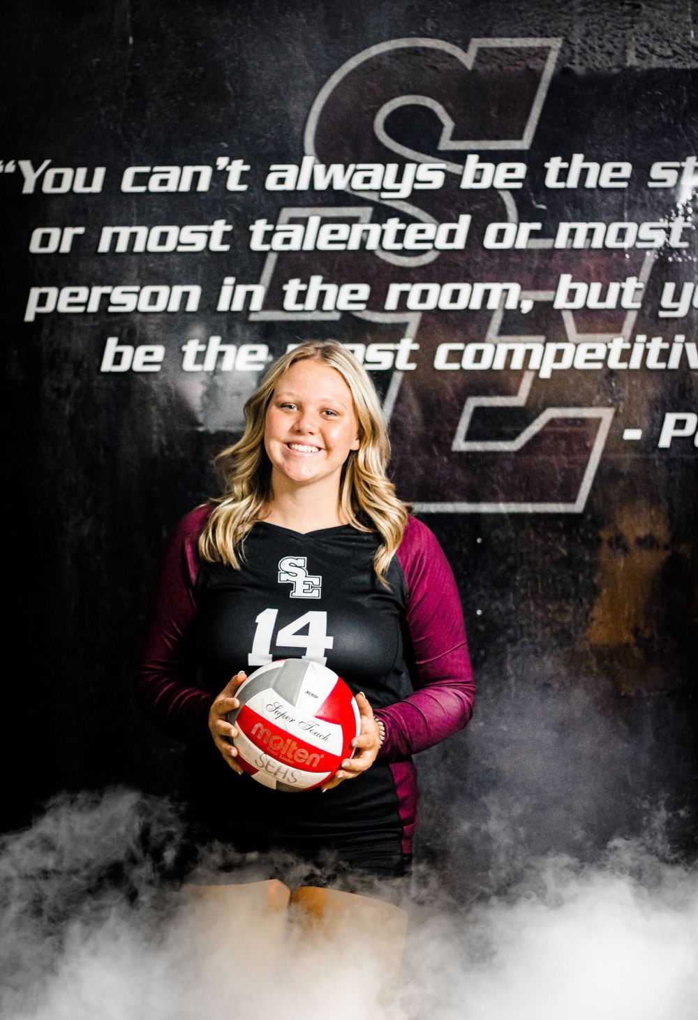 A volleyball player poses with a ball against a dark background with an inspirational quote.