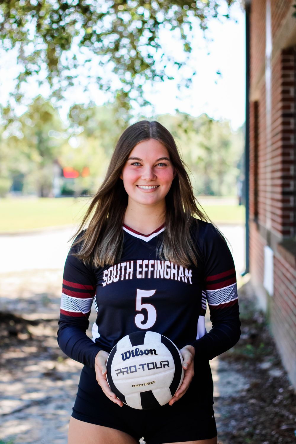 Volleyball player in South Effingham uniform poses outdoors with ball.