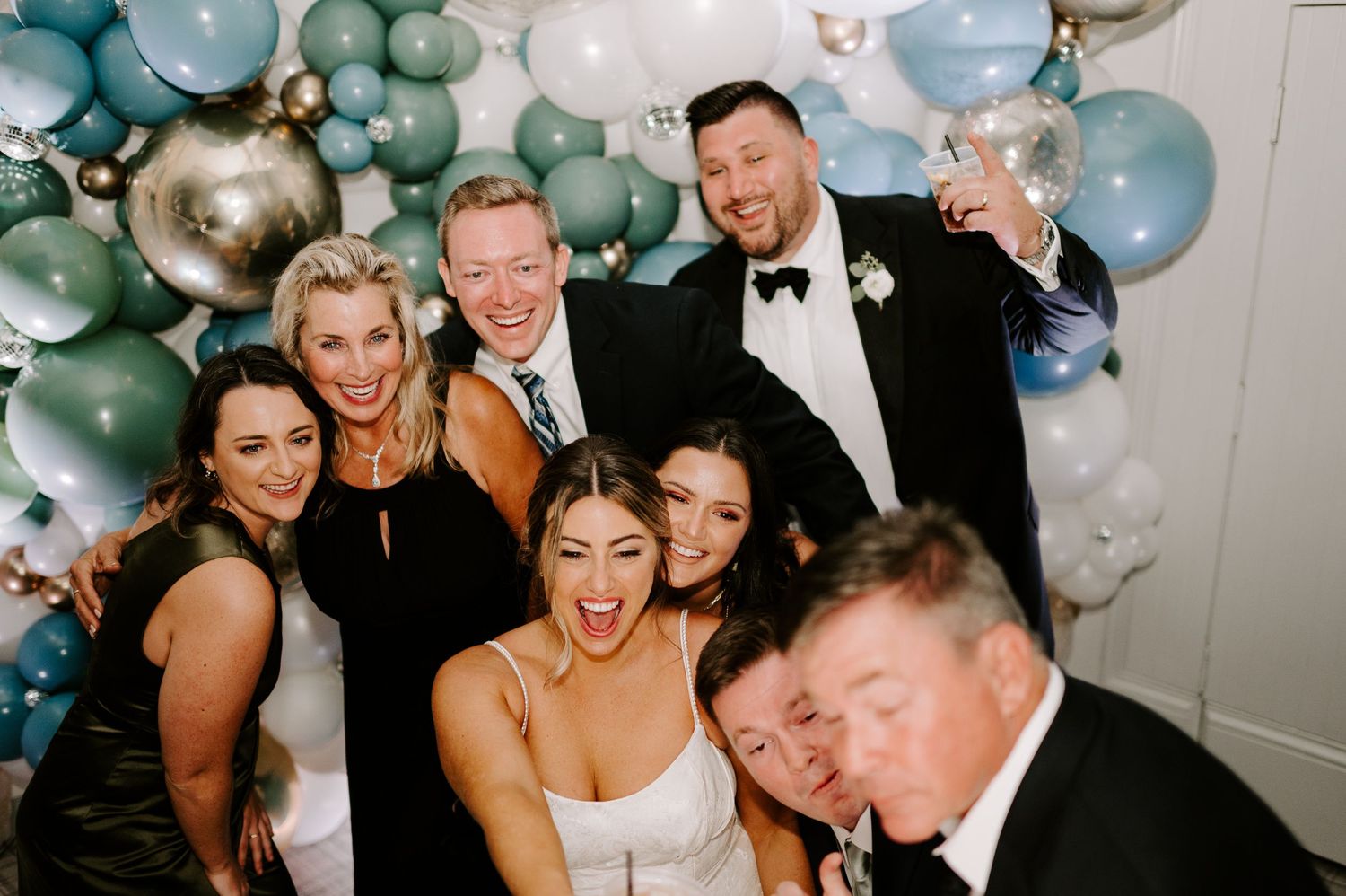Wedding celebration with blue and white balloon arch decorations and dancing guests.