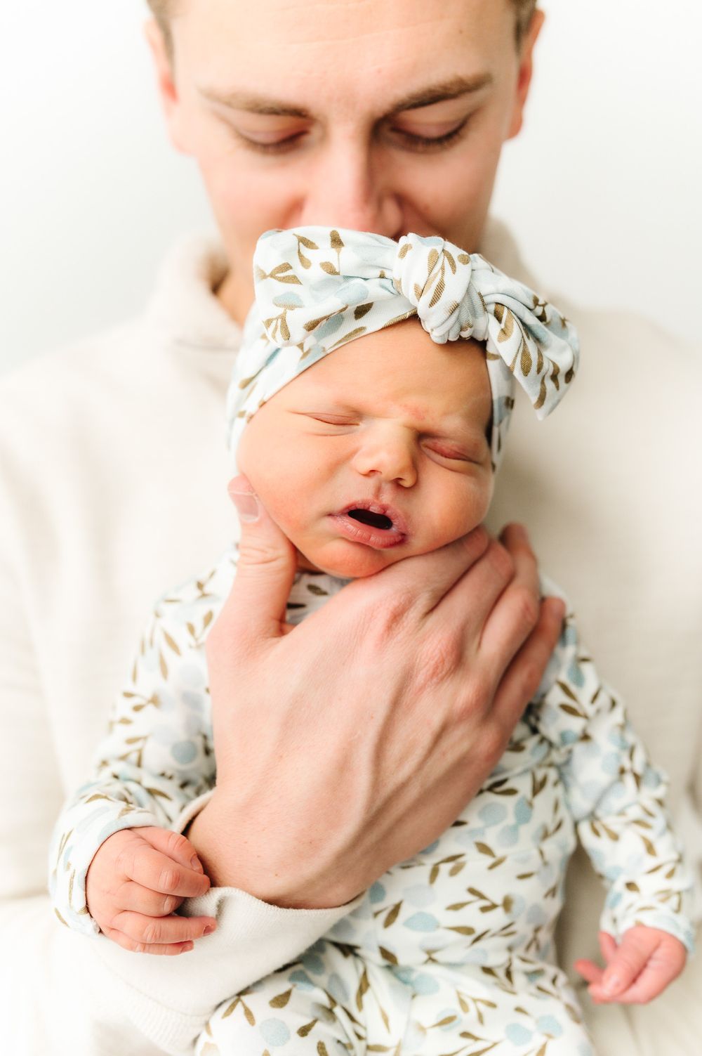 Close-up photos of a sleeping newborn wearing a patterned outfit with delicate details.