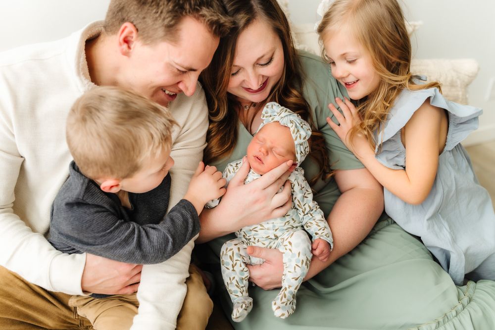 Family lifestyle photos showing tender moments with a newborn baby in a light, airy setting.