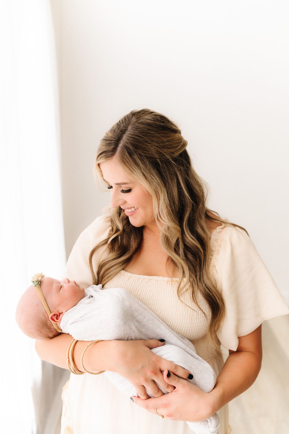 Soft, minimalist portraits showing tender moments between parent and baby in cream-colored clothing.