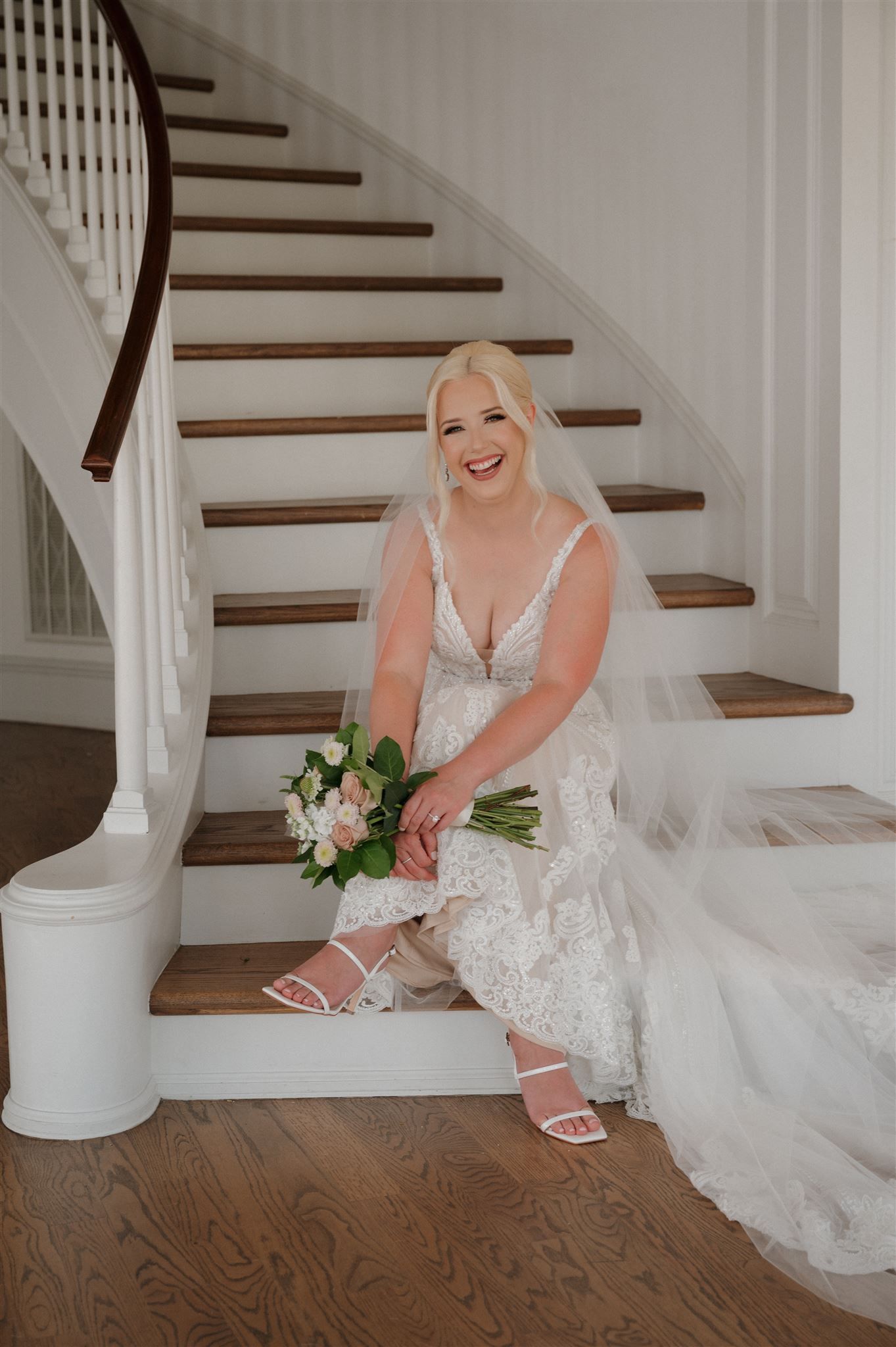 Candid bridal portrait on white staircase showing detailed lace gown and natural bouquet.