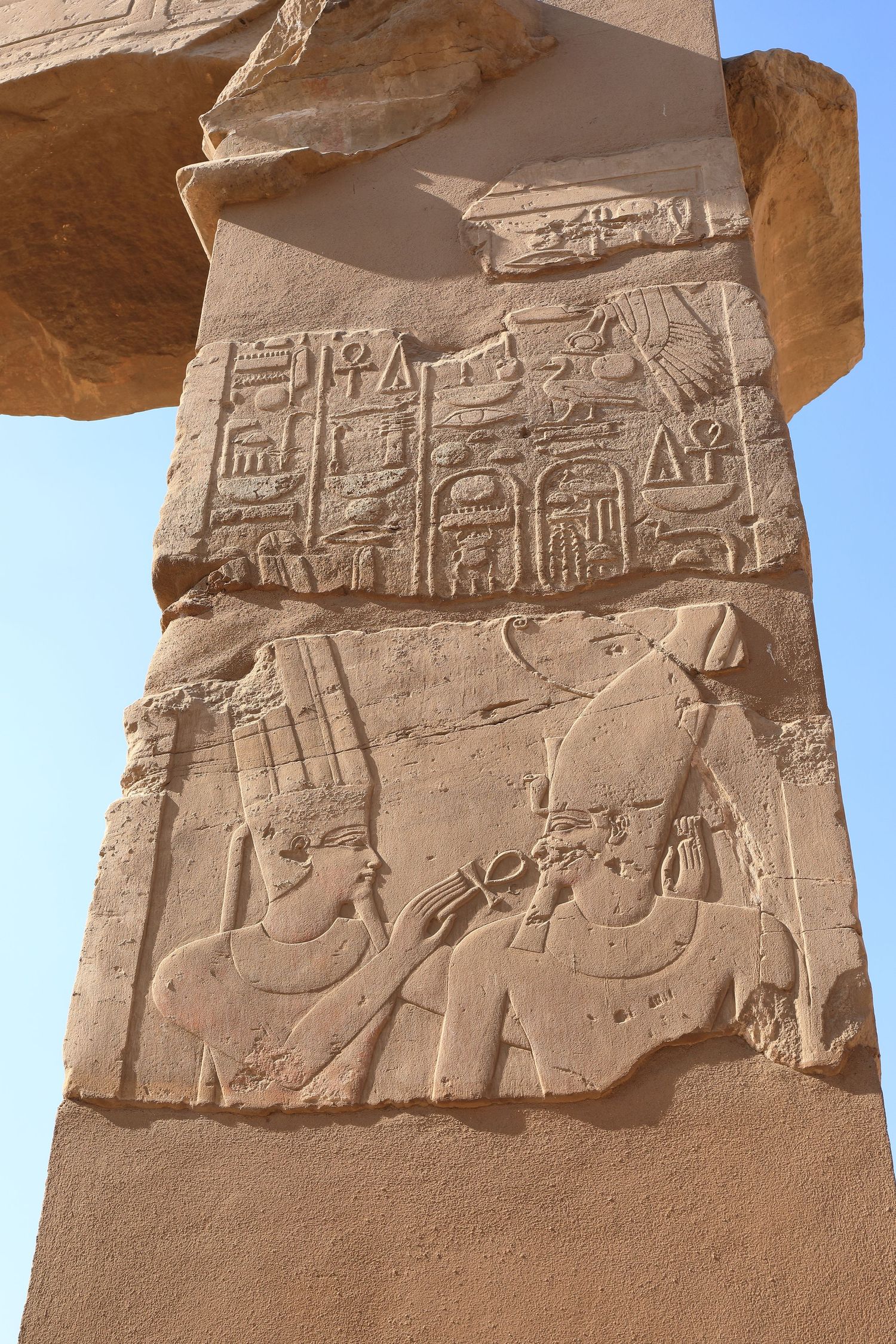 Ancient Egyptian hieroglyphics and carvings on sandstone temple wall showing figures and symbols.