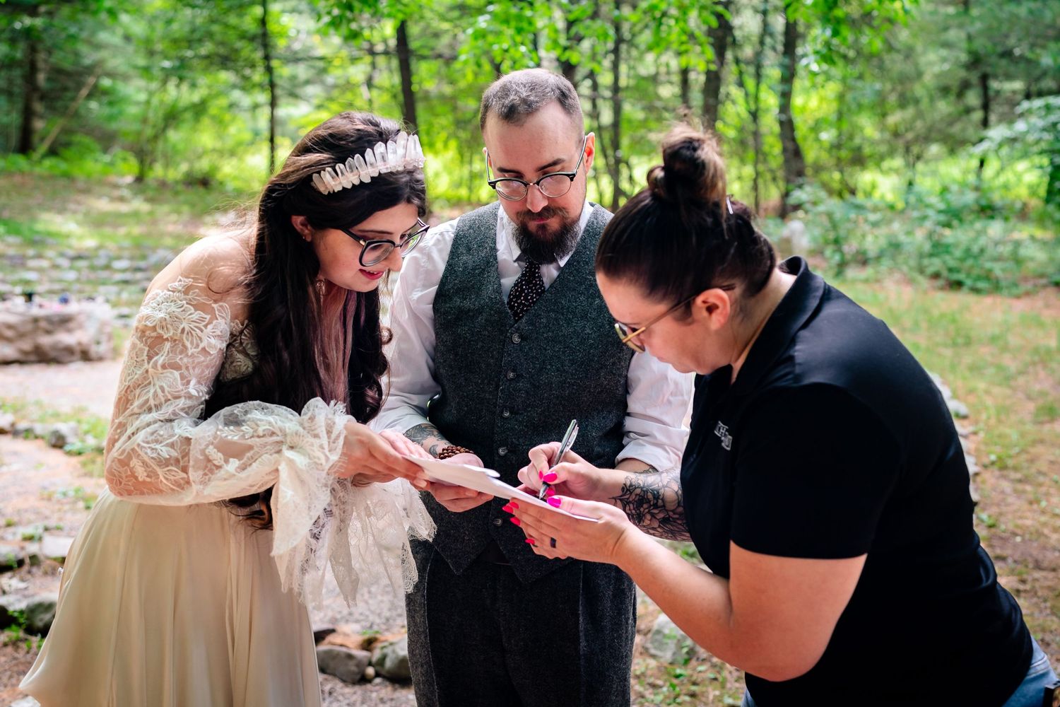 Wedding party members sharing emotional moments in a wooded setting.