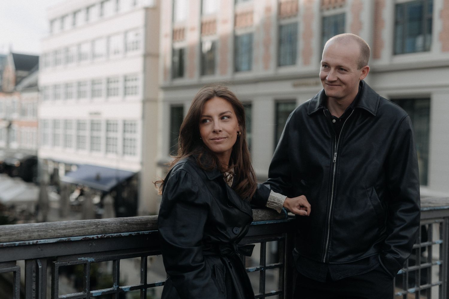 Couple having a conversation while standing on a city balcony on an overcast day.