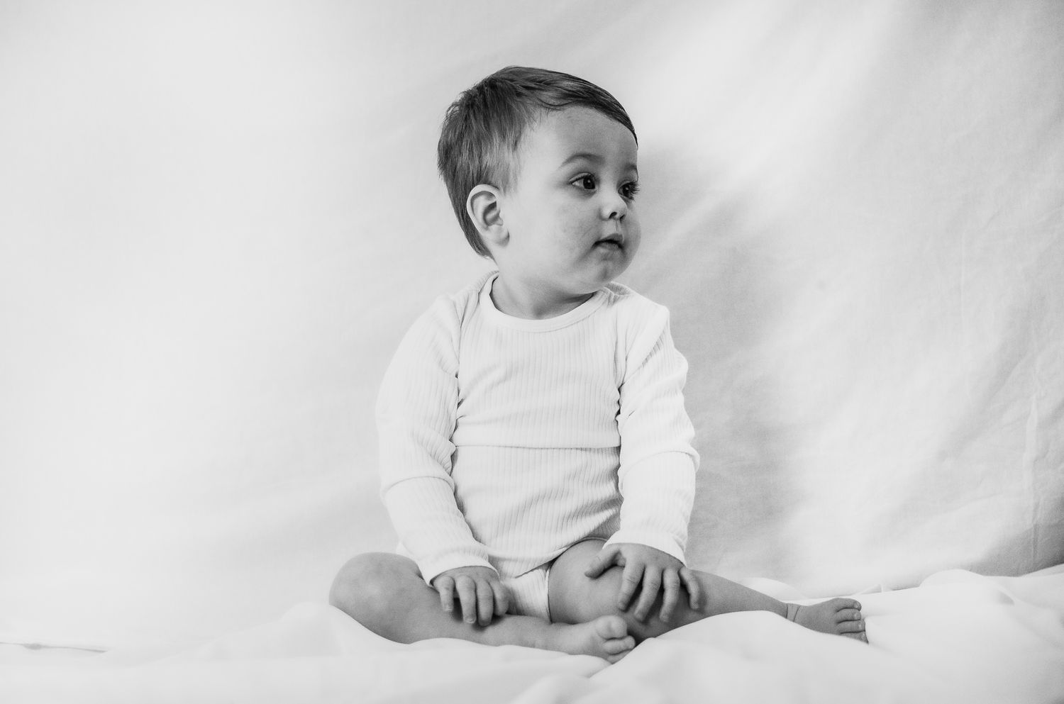 Simple black and white image of a toddler on a classic white setup
