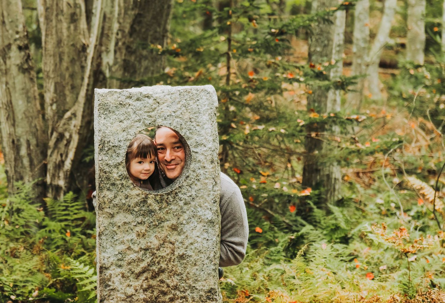 A dad and his adorable little daughter smile in a stone garden installation at the Maine Botanical Gardens.