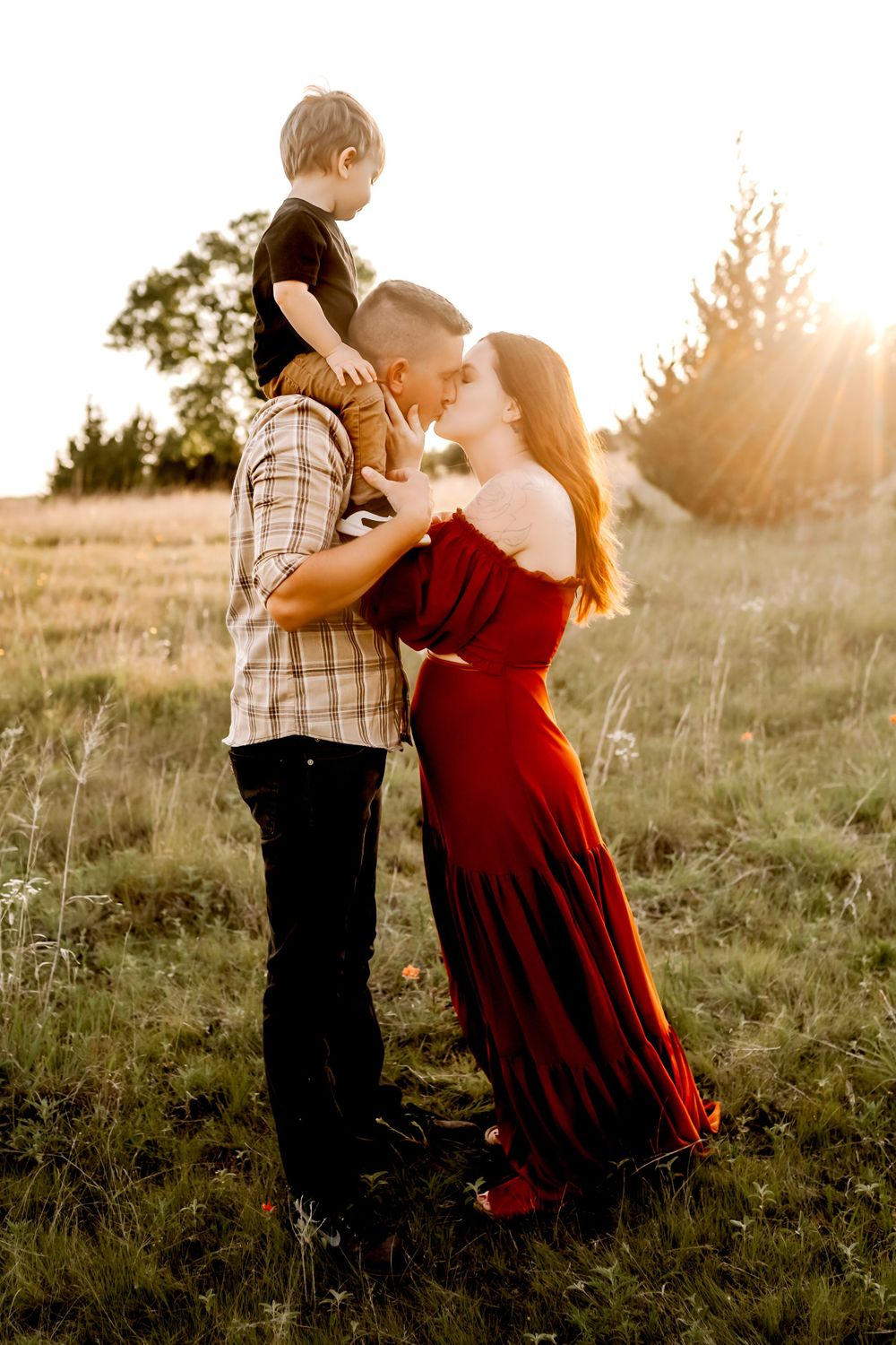 A sweet family portrait taken in a sunlit meadow with golden hour lighting.