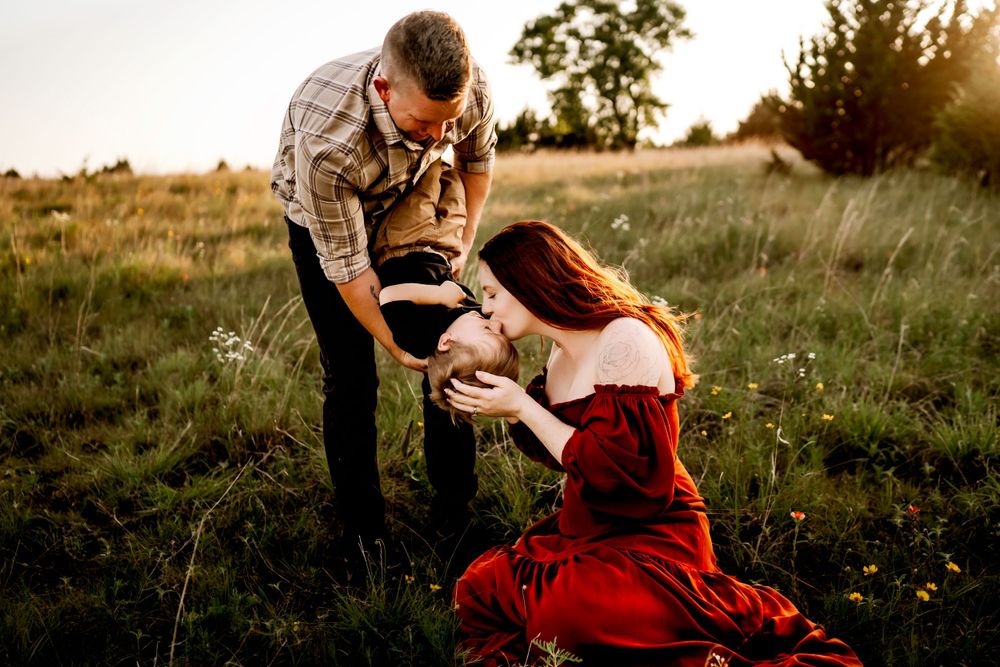 An emotional family moment captured in a sunlit field with natural lighting.