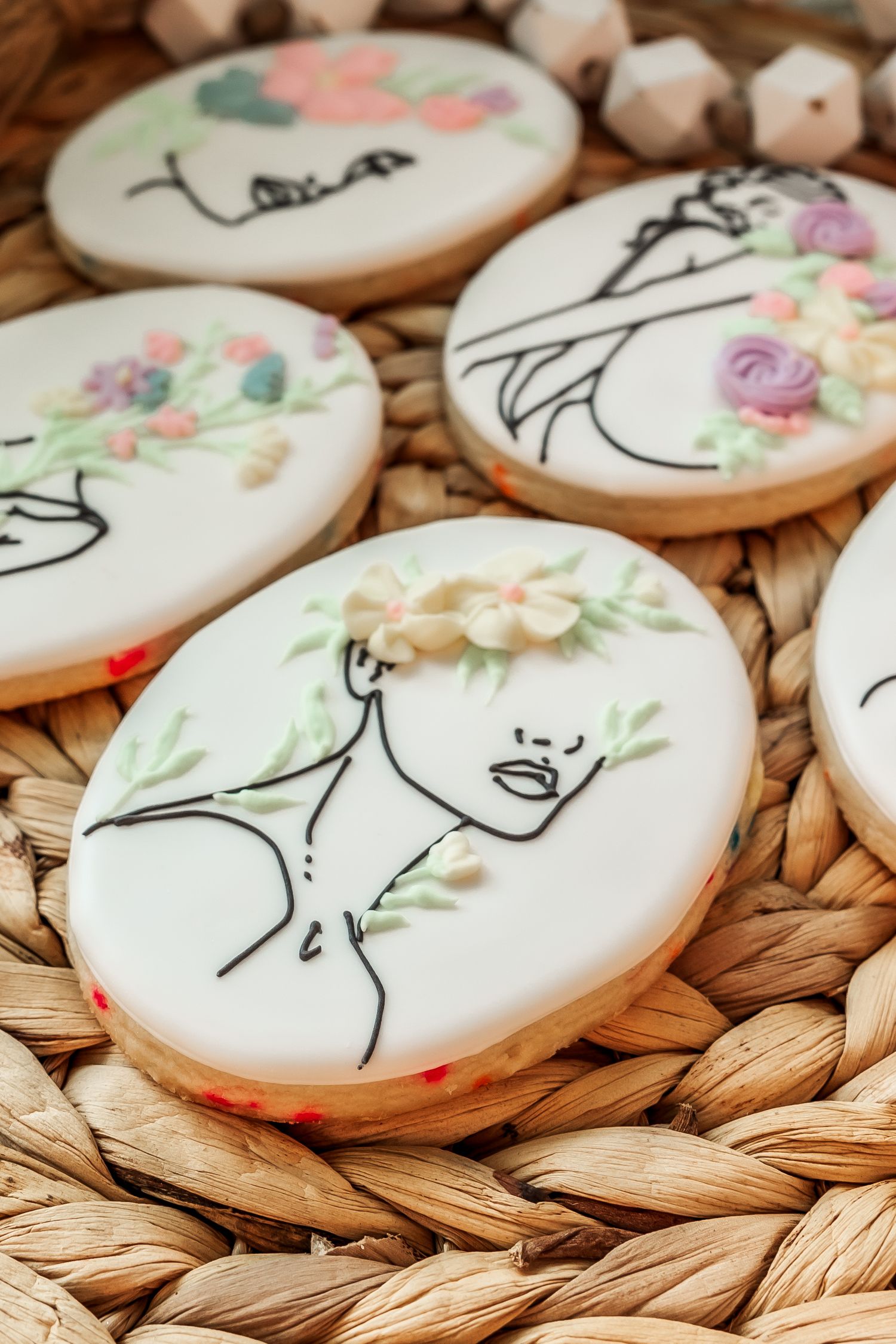 Hand-decorated sugar cookies featuring minimalist line art designs and pastel floral accents.